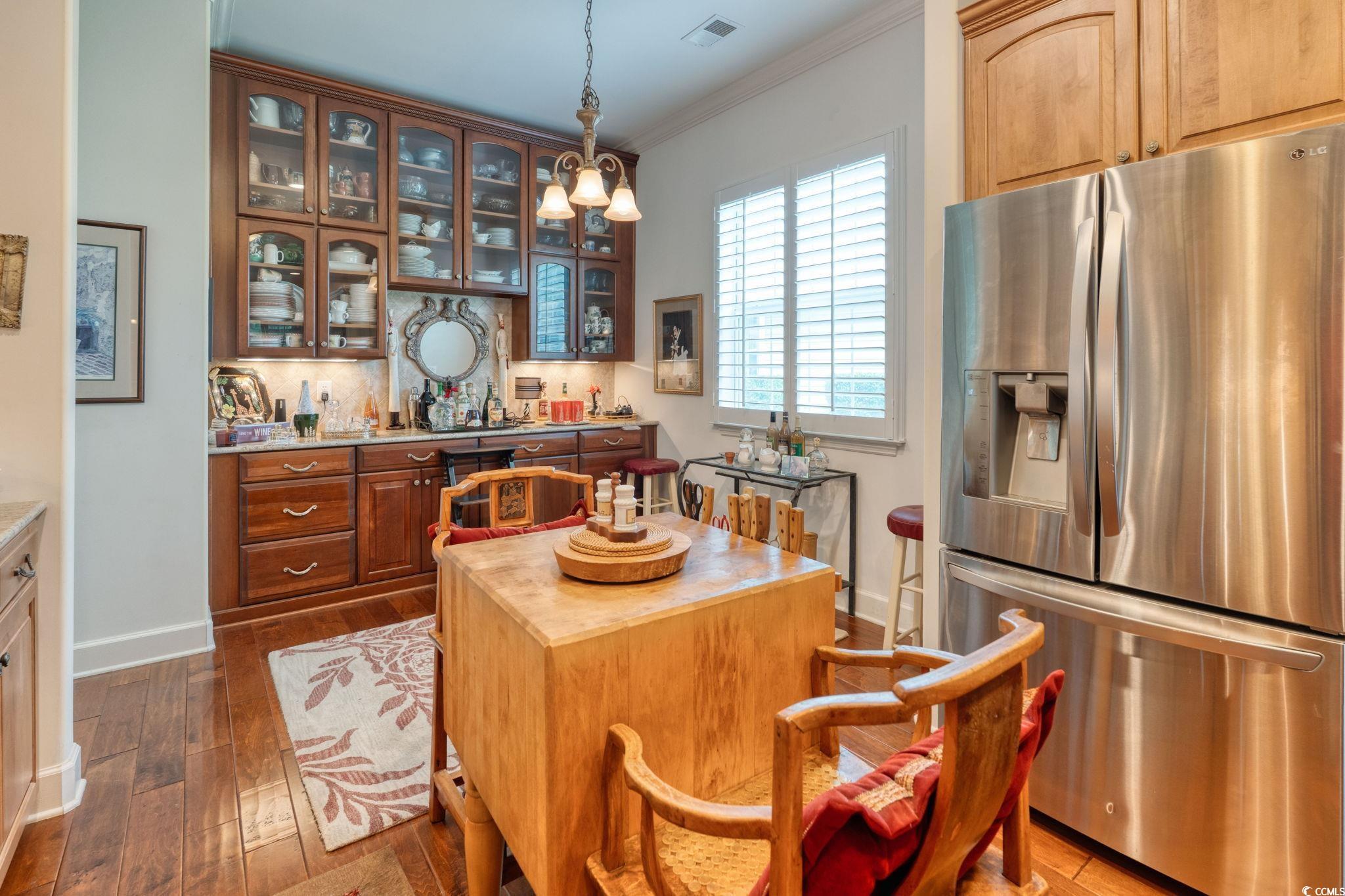 492 Grand Cypress Way Murrells Inlet, SC 29576 - Photo 12 of 40 Kitchen with stainless steel fridge, glass insert cabinets, crown molding, dark wood-style floors, and tasteful backsplash