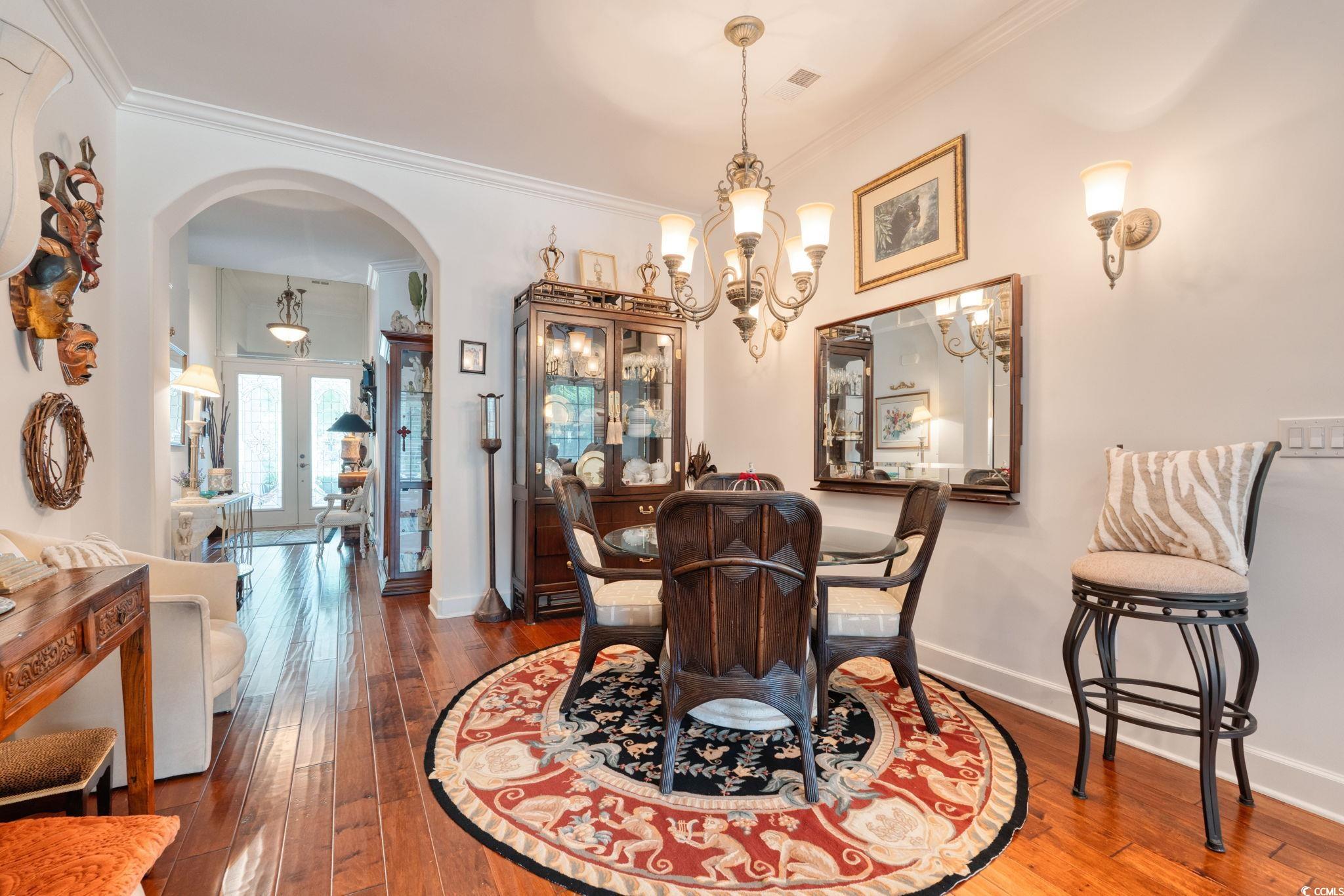 492 Grand Cypress Way Murrells Inlet, SC 29576 - Photo 5 of 40 Dining room featuring arched walkways, a chandelier, crown molding, wood-type flooring, and french doors