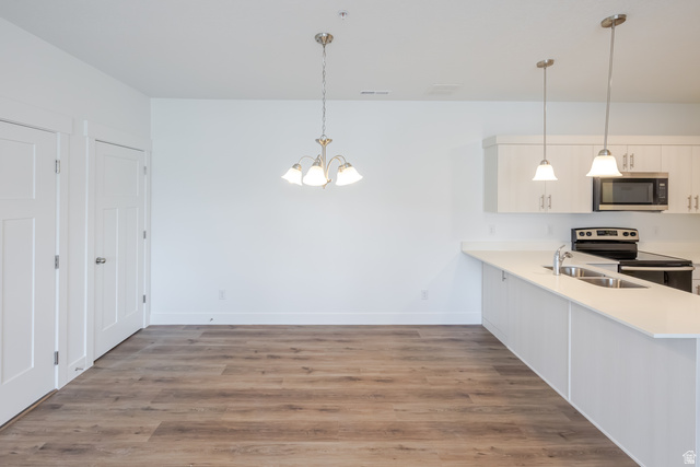 675 West 4500th South, Unit P302 Mapleton, UT 84664 - Photo 13 of 16 Open-concept living space featuring wood-finish flooring, white walls, and a contemporary kitchen with white cabinetry and light-colored countertops