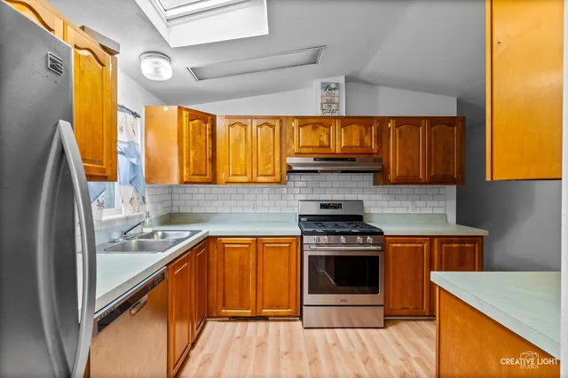 a kitchen with stainless steel appliances granite countertop a sink stove and refrigerator