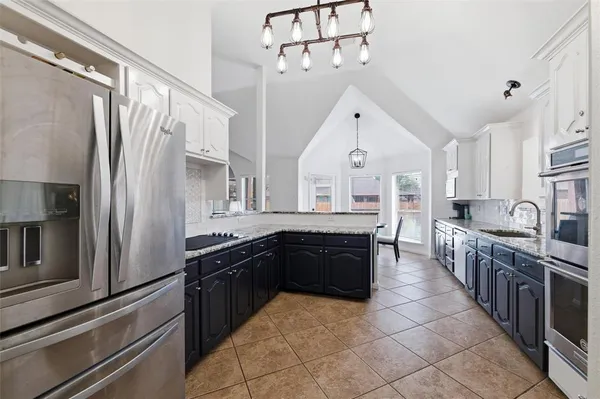 a large kitchen with granite countertop a refrigerator and a sink