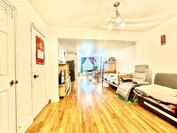 a living room with couches and kitchen view with wooden floor