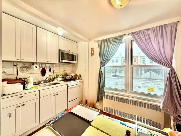 a kitchen with stainless steel appliances a sink a stove and white cabinets with wooden floor