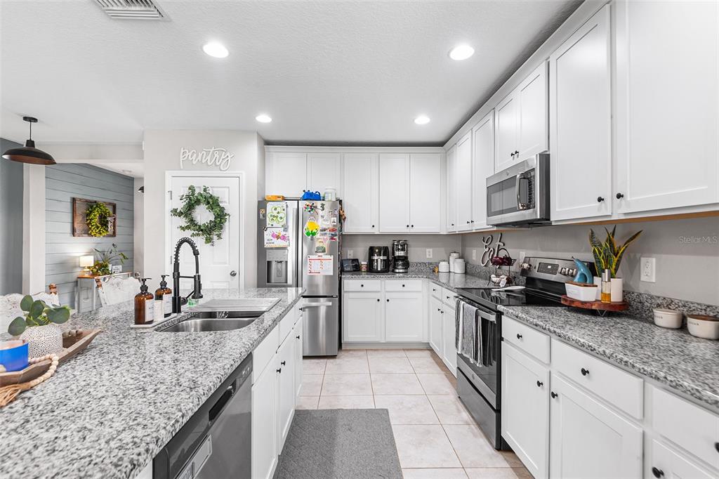 12960 Conquistador Loop Spring Hill, FL 34610 - Photo 8 of 26 a kitchen with granite countertop a sink stainless steel appliances and white cabinets