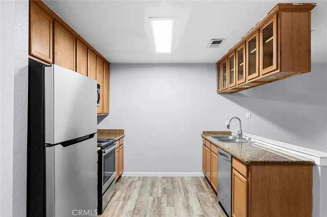 a kitchen with stainless steel appliances granite countertop a refrigerator a stove and a sink with wooden cabinets