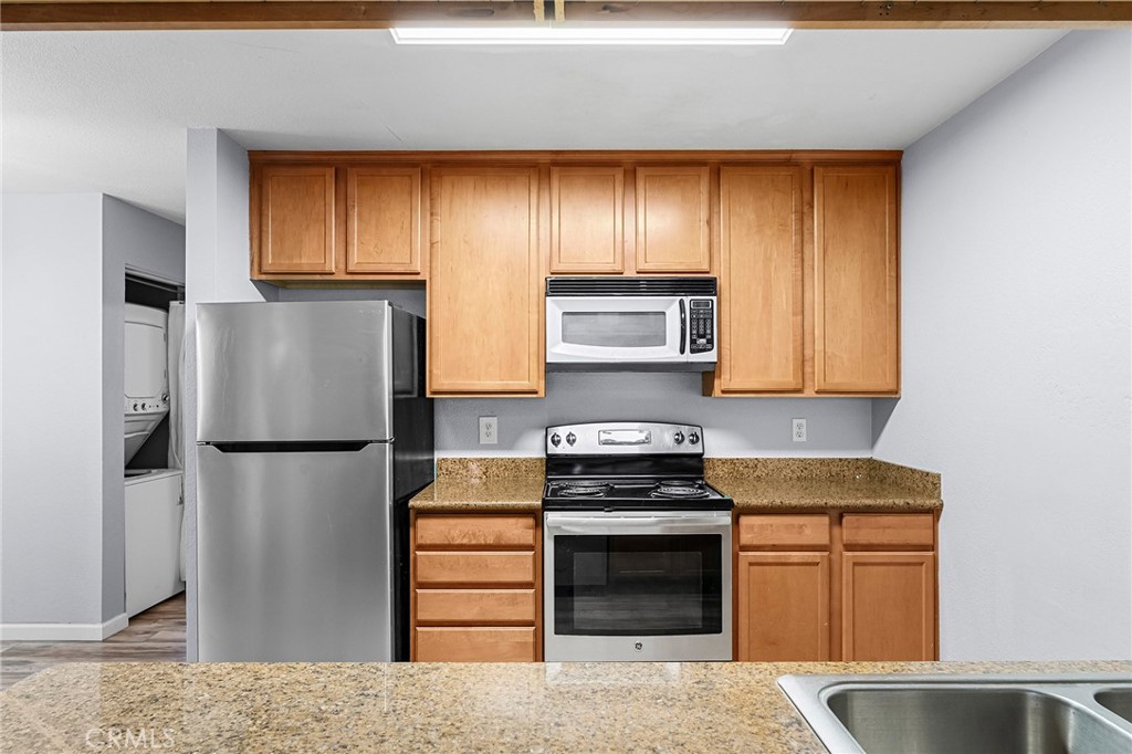 1114 Nord Avenue, Unit 11 Chico, CA 95926 - Photo 30 of 47 a kitchen with stainless steel appliances granite countertop a refrigerator a stove and a sink with wooden cabinets