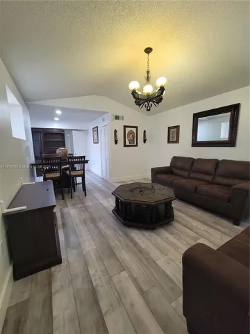 a living room with furniture kitchen view and a chandelier