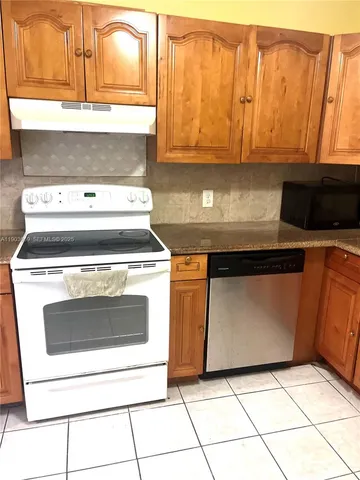 a stove top oven sitting inside of a kitchen with stainless steel appliances wooden floor a stove a microwave and a refrigerator