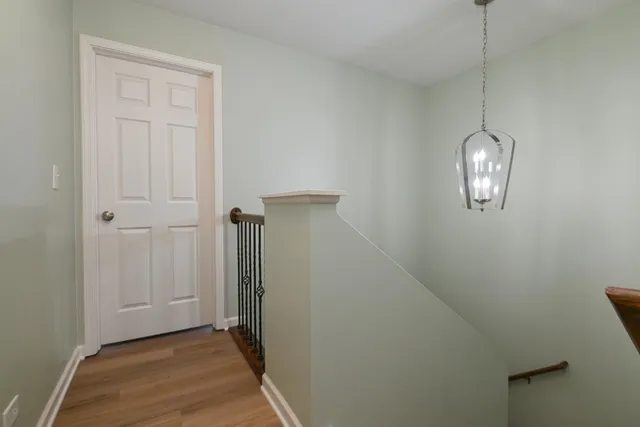 a view of a hallway with chandelier fan and wooden floor