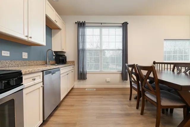 a kitchen with stainless steel appliances granite countertop a kitchen island hardwood floor sink stove dining table and chairs