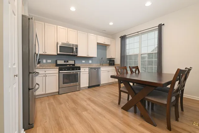 a kitchen with a stove a sink a microwave a dining table and chairs