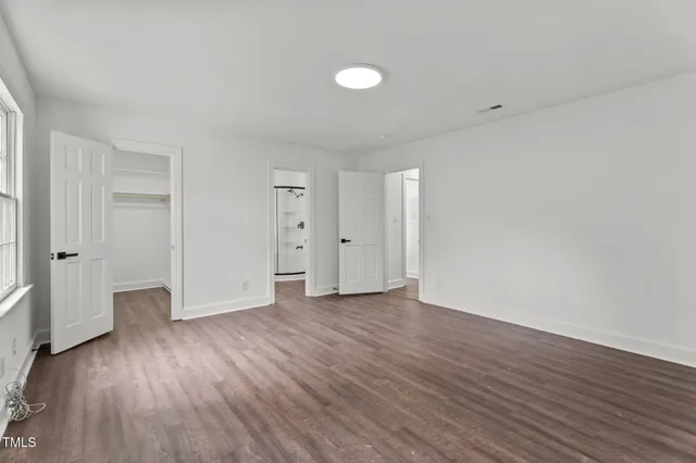 a view of an empty room with wooden floor and window