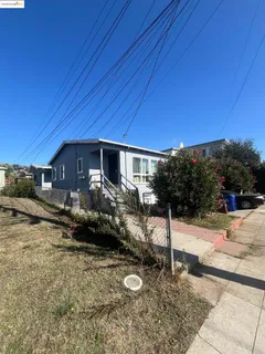 a backyard of a house with table and chairs under an umbrella