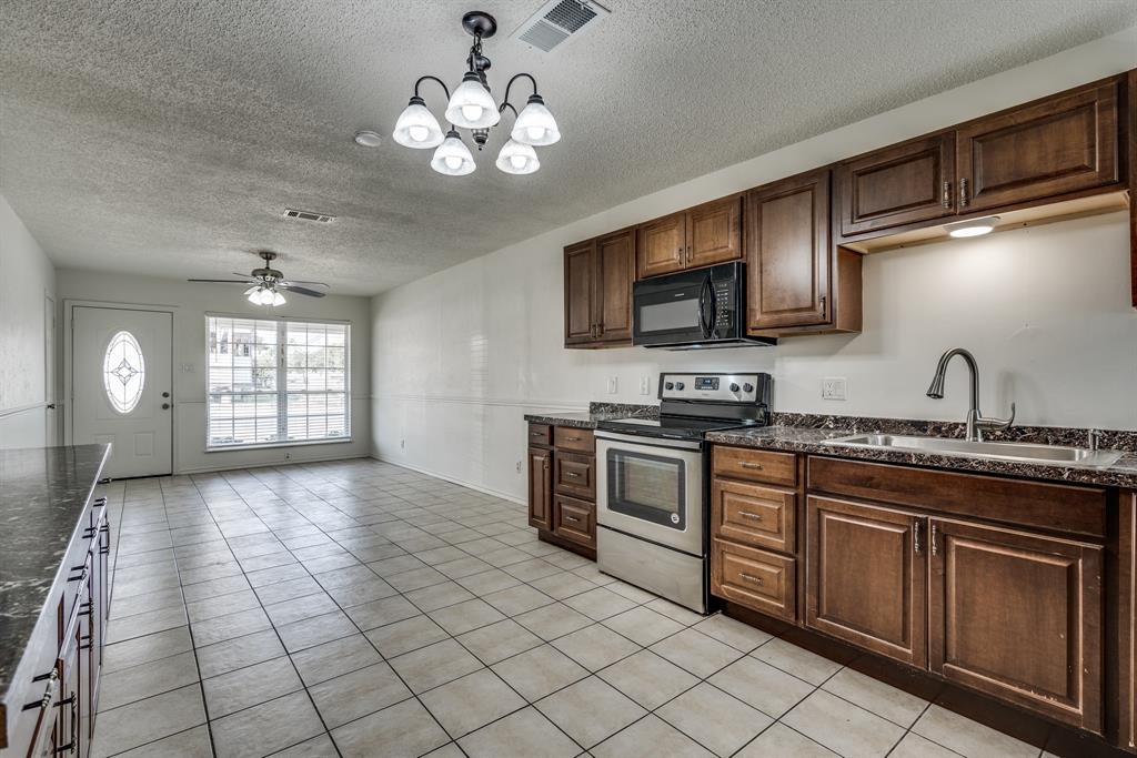 116 North 12th Street, Unit B Midlothian, TX 76065 - Photo 12 of 24 a kitchen with stainless steel appliances granite countertop a stove a sink and a microwave