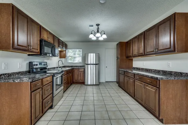 a kitchen with stainless steel appliances granite countertop a stove a sink dishwasher and a refrigerator