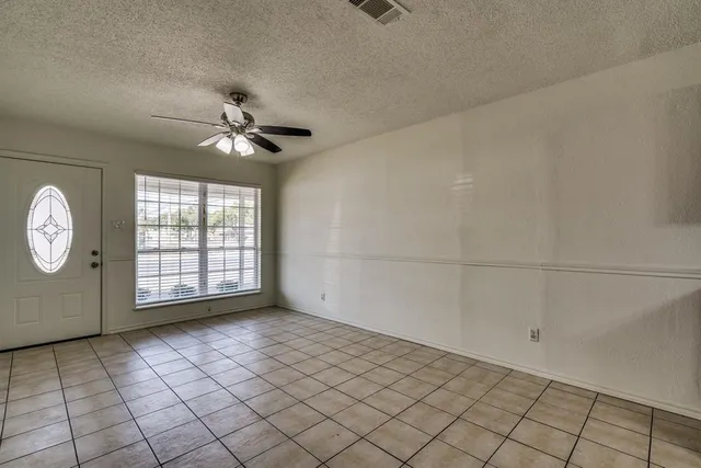 an empty room with windows and ceiling fan