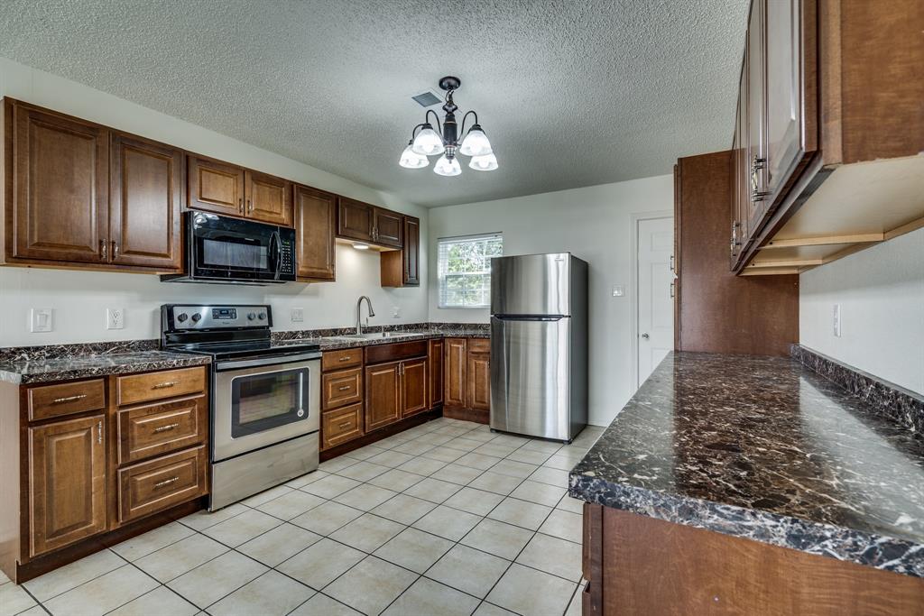 116 North 12th Street, Unit B Midlothian, TX 76065 - Photo 22 of 24 a kitchen with granite countertop a refrigerator stove top oven and sink