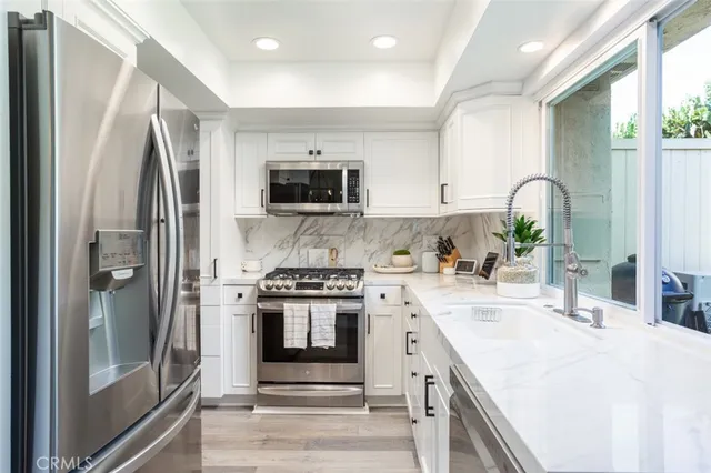 a kitchen with stainless steel appliances granite countertop a stove a sink and a refrigerator
