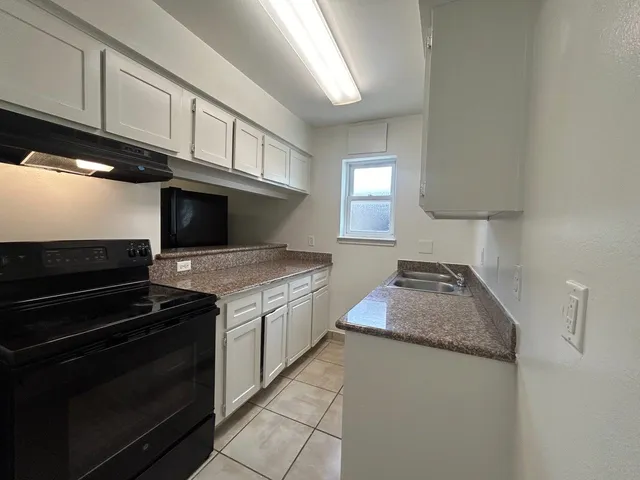 a kitchen with granite countertop a stove and a sink