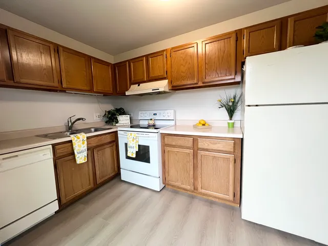 a kitchen with cabinets a sink and white appliances