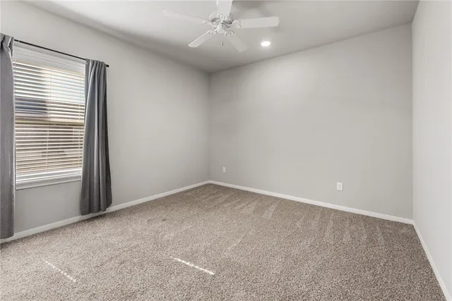 an empty room with a ceiling fan and window