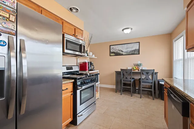 a kitchen with stainless steel appliances granite countertop a stove top oven a sink a dining table and chairs