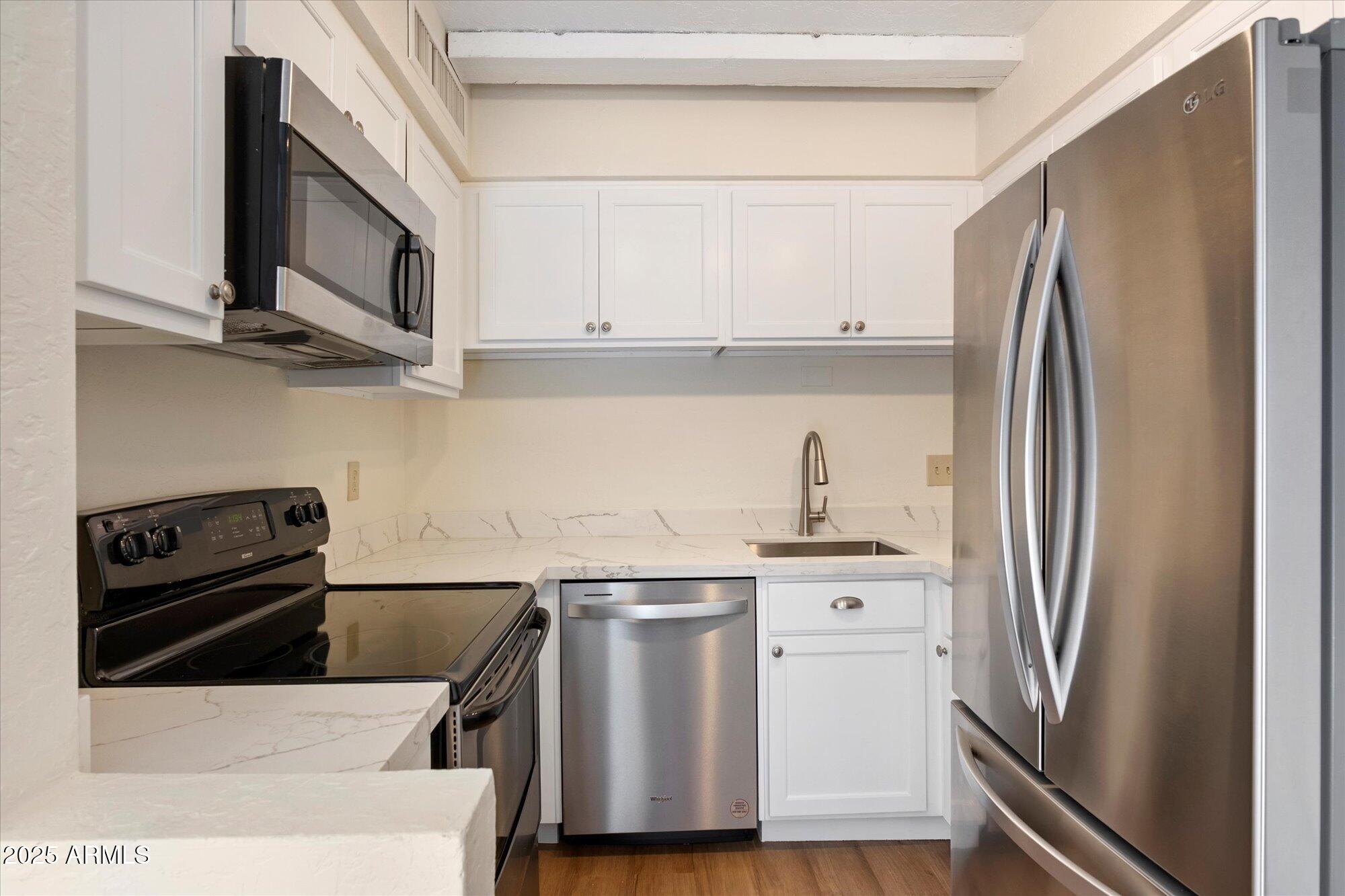 1014 East Osborn Road, Unit A Phoenix, AZ 85014 - Photo 8 of 25 a kitchen with stainless steel appliances a refrigerator a stove and a sink