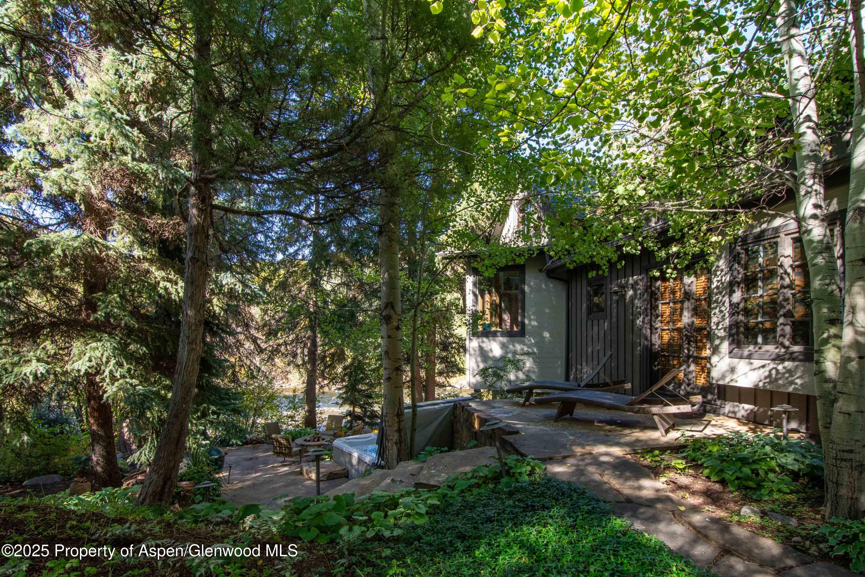 4076 Lower River Road Snowmass, CO 81654 - Photo 50 of 71 a view of a backyard with a table and chairs and a large tree