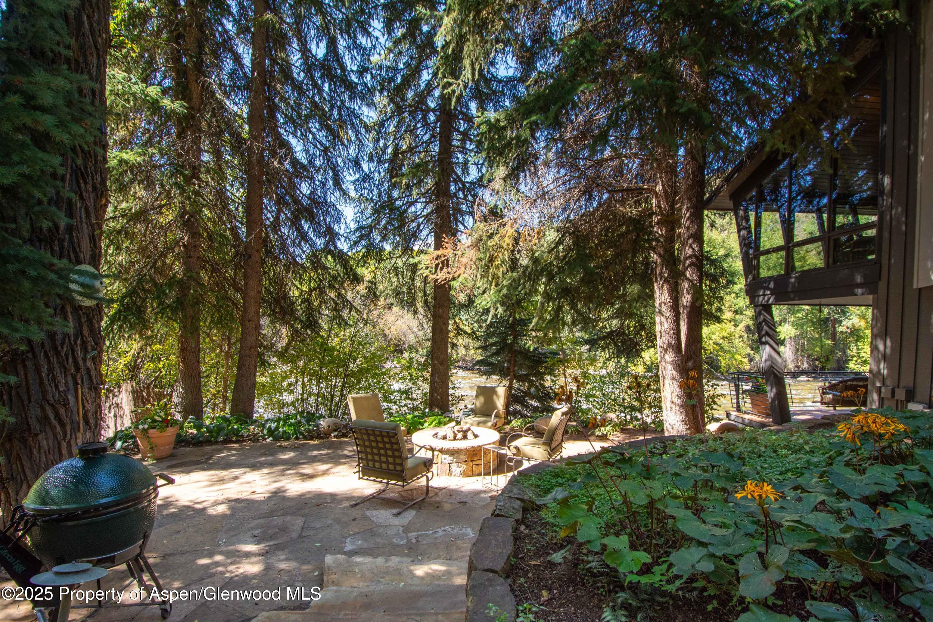 4076 Lower River Road Snowmass, CO 81654 - Photo 55 of 71 a backyard of a house with table and chairs under an umbrella