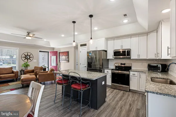 a large kitchen with stainless steel appliances granite countertop a refrigerator a stove a sink a dining table and chairs with wooden floor