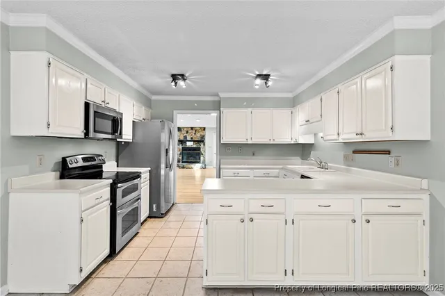 a kitchen with stainless steel appliances granite countertop a stove top oven a refrigerator a sink and white cabinets