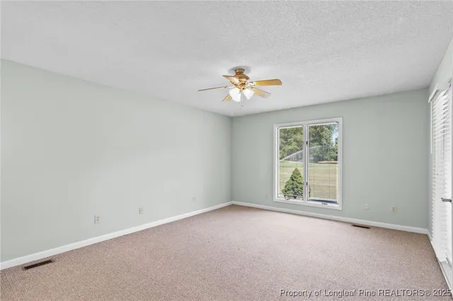 an empty room with a window and a ceiling fan