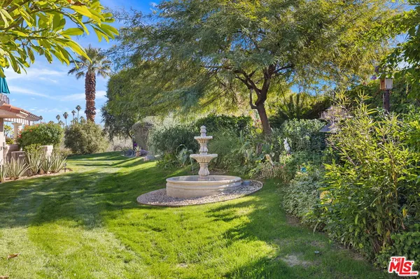 a view of a fountain in a yard with plants and trees