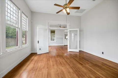 a view of empty room with wooden floor and fan