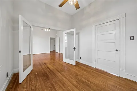 a view of a room with wooden floor a ceiling fan and windows