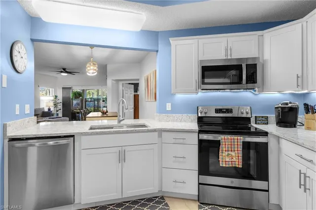 a kitchen with granite countertop white cabinets and stainless steel appliances