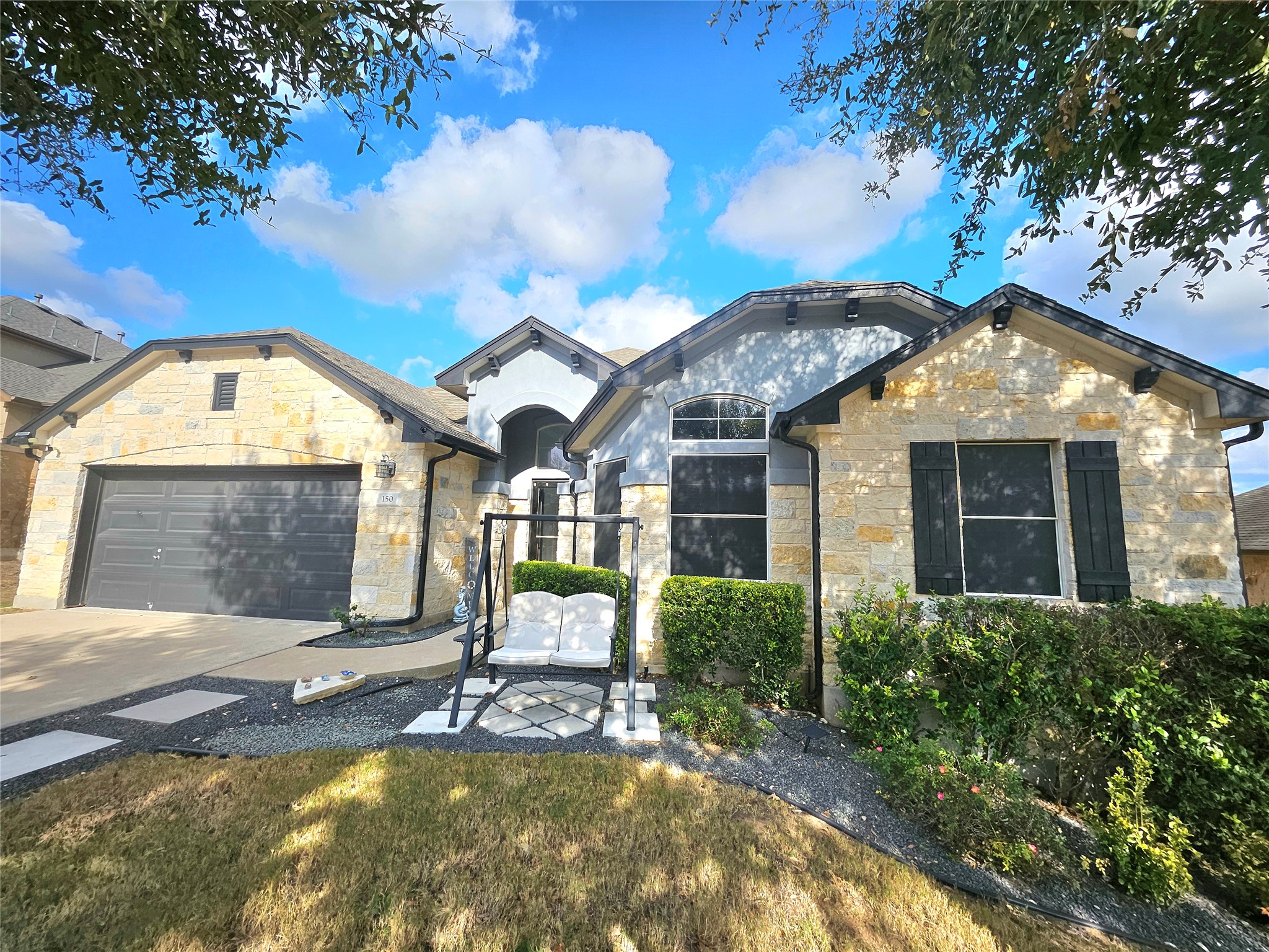150 Manchester Lane Austin, TX 78737 - Photo 24 of 24 View of front facade featuring stone siding, driveway, and a garage