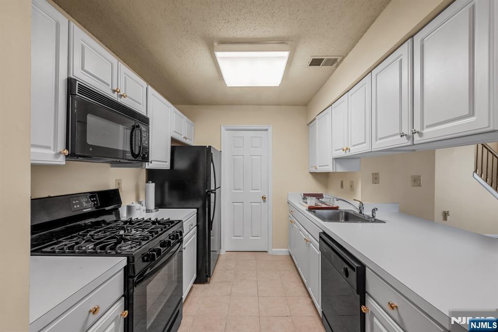 159 Market Street, Unit 1411 Newark, NJ 07102 - Photo 6 of 19 a kitchen with a stove a sink and a microwave