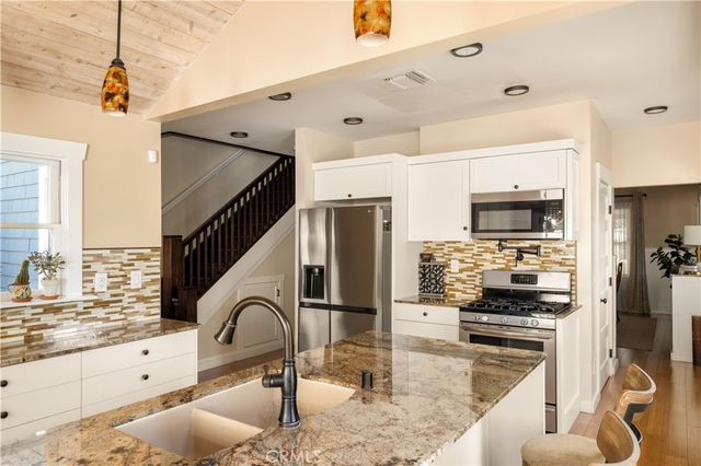 a kitchen with granite countertop a stove a sink and a microwave