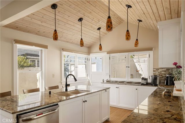 a kitchen with stainless steel appliances granite countertop a sink dishwasher and white cabinets with wooden floor