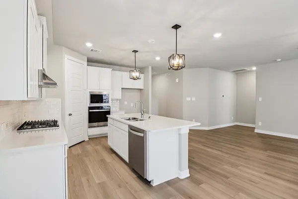 a kitchen with a sink a stove a refrigerator and a wooden floor
