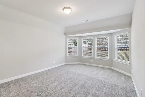 a bedroom with a bed a couch and a flat tv screen next to a window