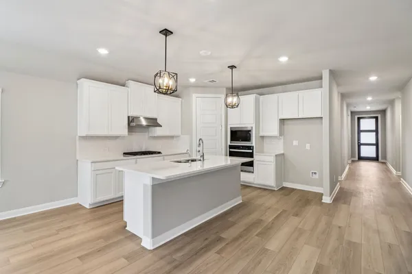 a large kitchen with stainless steel appliances granite countertop a large center island a stove a refrigerator and a view of living room