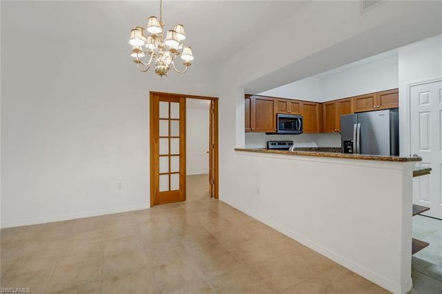 an empty room with chandelier fan and windows