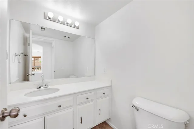 a bathroom with a toilet sink double vanity and mirror