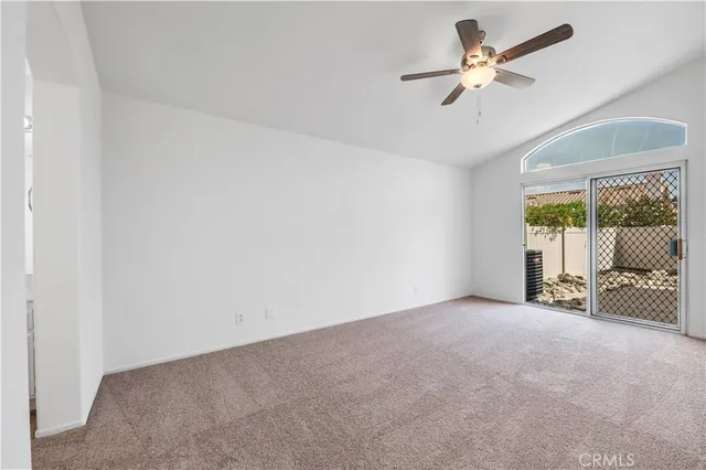 an empty room with a ceiling fan and a large window