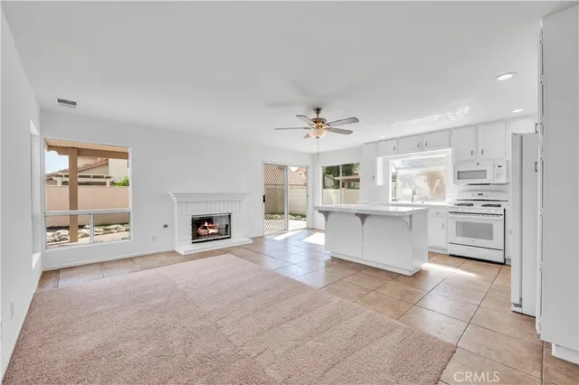 a large white kitchen with a fireplace and chandelier