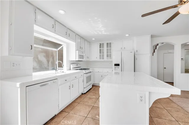 a large white kitchen with stainless steel appliances granite countertop a sink and a refrigerator