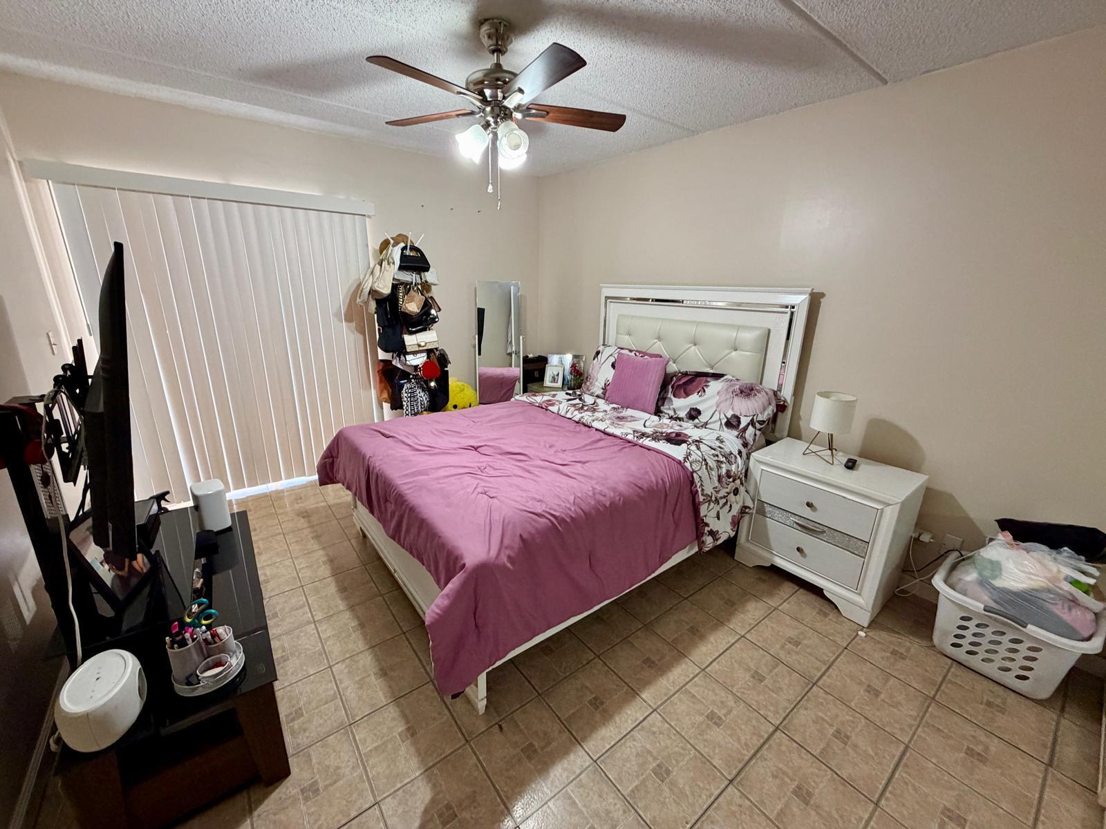 2000 Springdale Boulevard, Unit 102 Palm Springs, FL 33461 - Photo 6 of 11 a bedroom with a bed and a chandelier