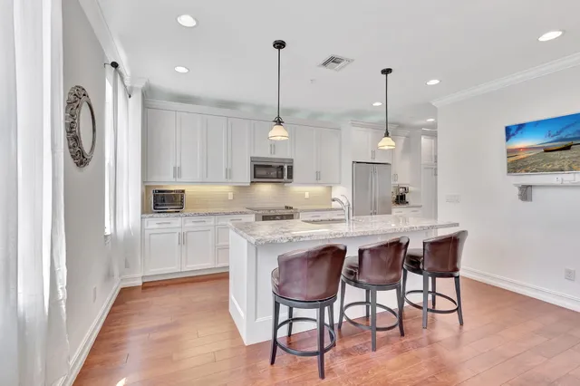 a kitchen with stainless steel appliances granite countertop a sink a stove a refrigerator and island with wooden floor